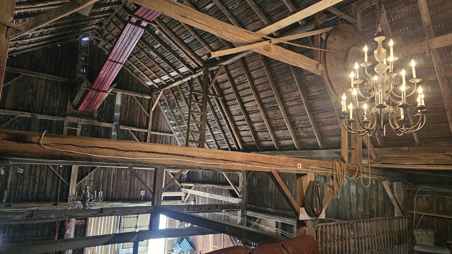 Chandelier and timber roof beams seen from the barn floor
